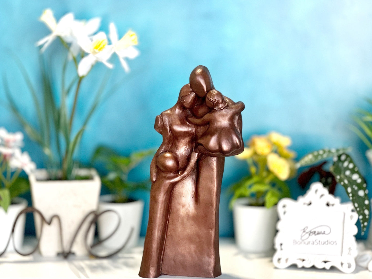 Copper Family of Four Sculpture with the dad holding a toddler girl and the little by hugging his mom.