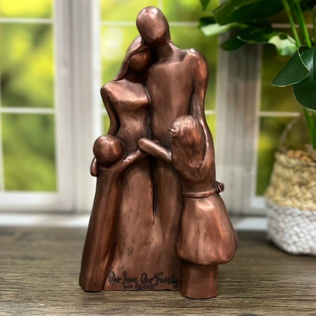 A copper family of four sculpture with two children hugging their parents in a Family Hug! The front of the sculpture is engraved with &quot;Our Love, Our Family&quot;