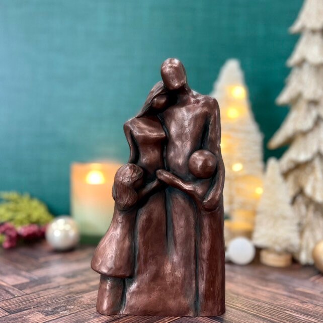 A copper family of four sculpture with two children hugging their parents in a Family Hug!