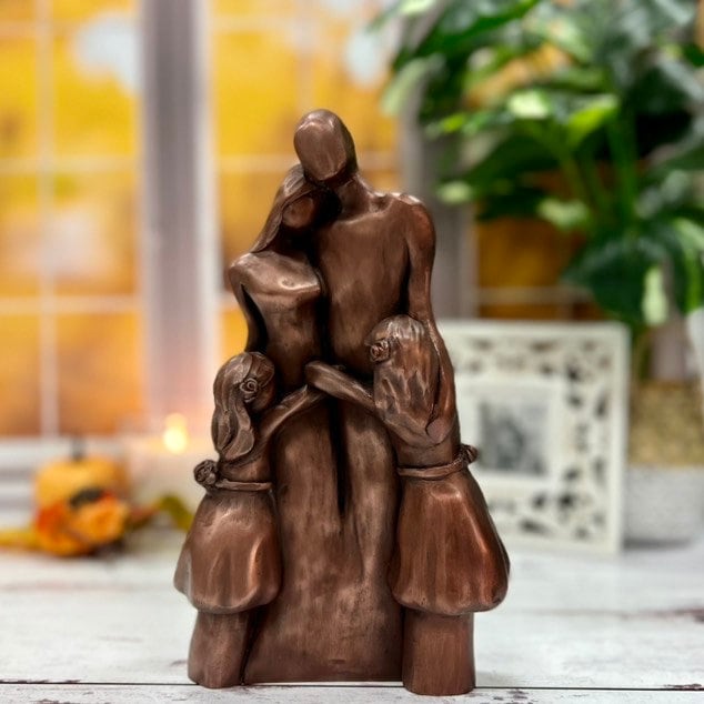 A copper family of four sculpture with two girls hugging their parents in a Family Hug!